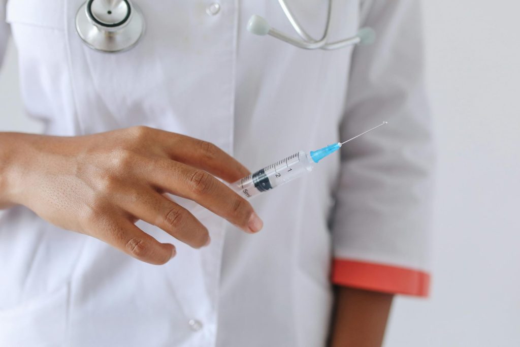 Close-up of a healthcare professional holding a vitamin injection, ready for injection. Focus on hand and syringe.